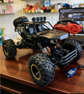 Toy monster truck with large wheels on a wooden surface, with a blurred background of a room.