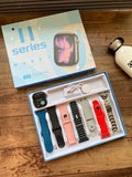 Apple Watch 11 Series smartwatch kit displayed on a wooden surface, showing the retail box, the open tray with a watch and multiple colorful bands, and a white bottle nearby.