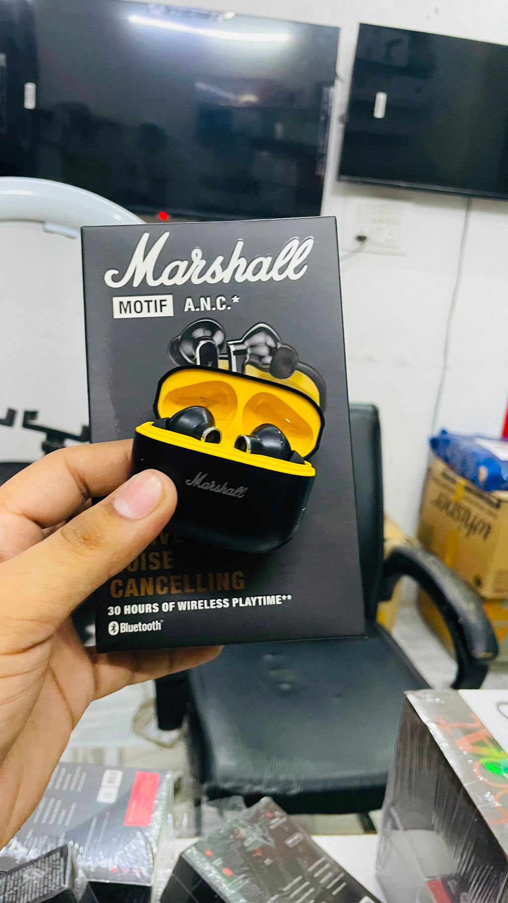 A hand holds a boxed pair of Marshall MOTIF A.N.