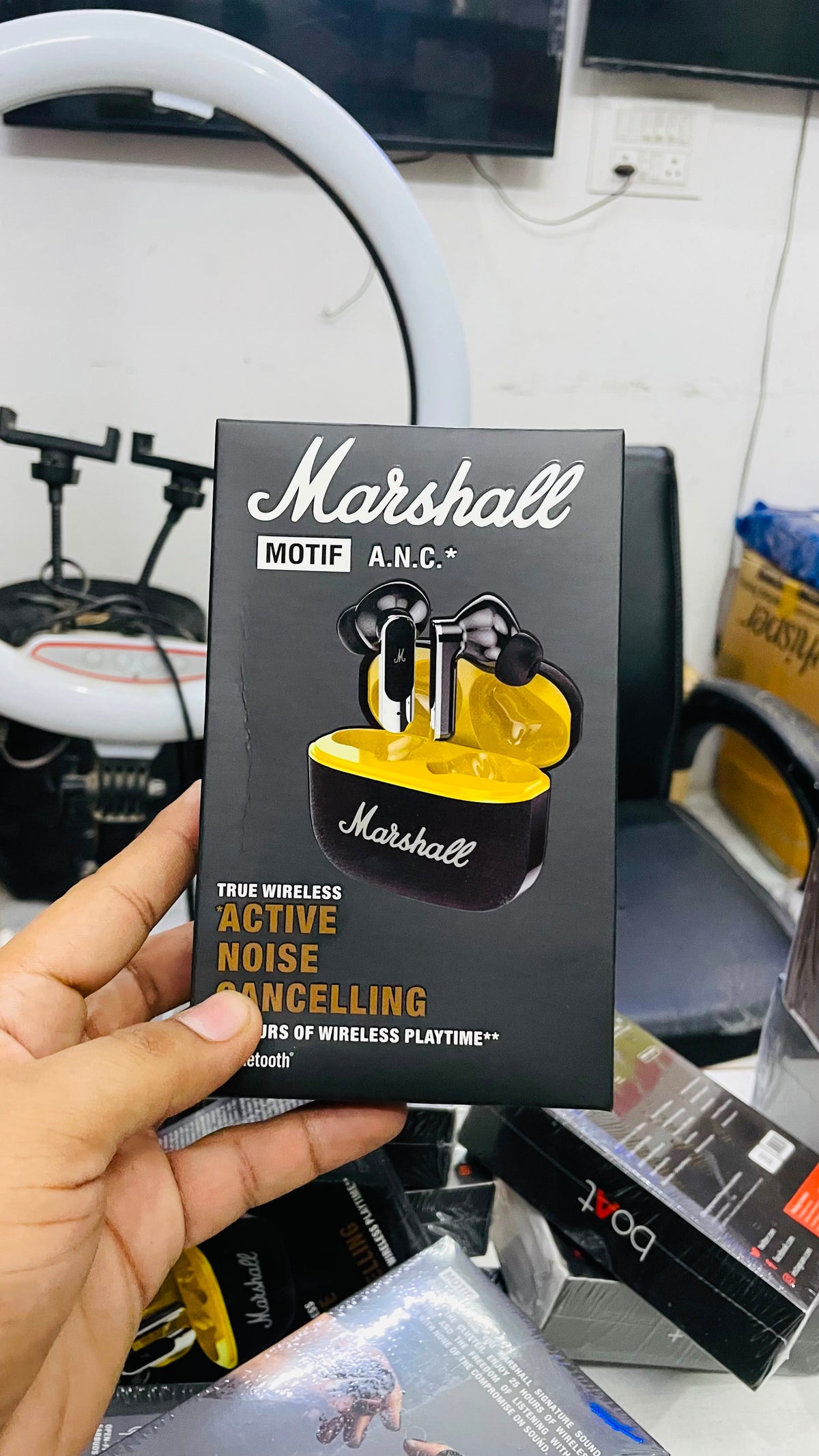 A hand holds a black box of Marshall MOTIF A.N.